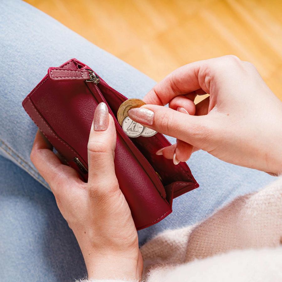 Red RFID-blocking women's leather trifold wallet shown in hand, highlighting slim design and secure zipper closure