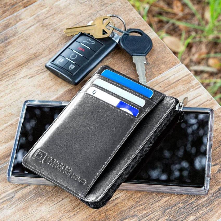 Black RFID-blocking mini wallet next to every day carry items highlighting its compact design and stylish appearance. The wallet is shown with its secure closure and multiple compartments, making it a practical accessory for organizing essentials like credit cards, IDs, and cash while on the go.